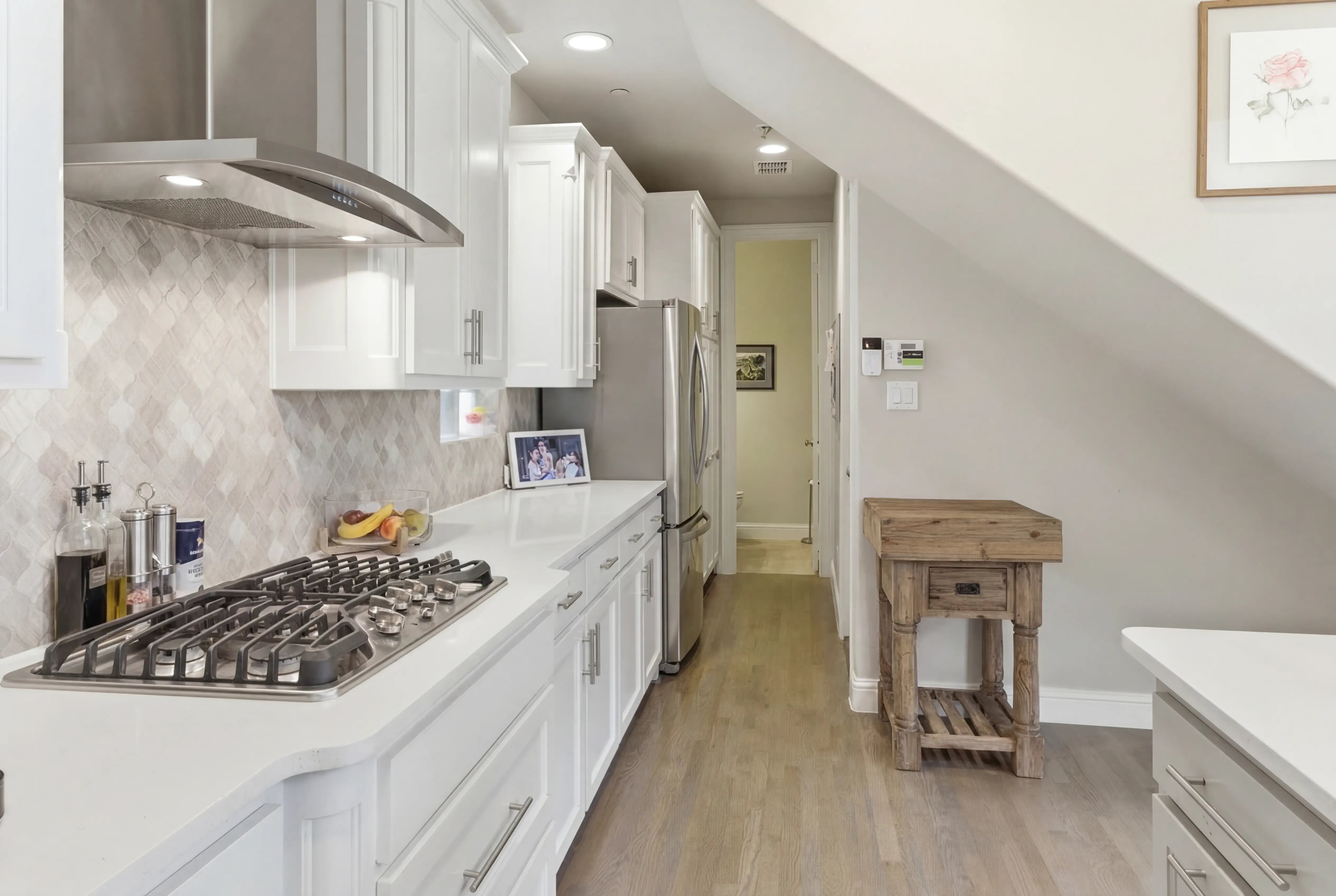 Gas cooktop with herringbone stone backsplash and stainless hood